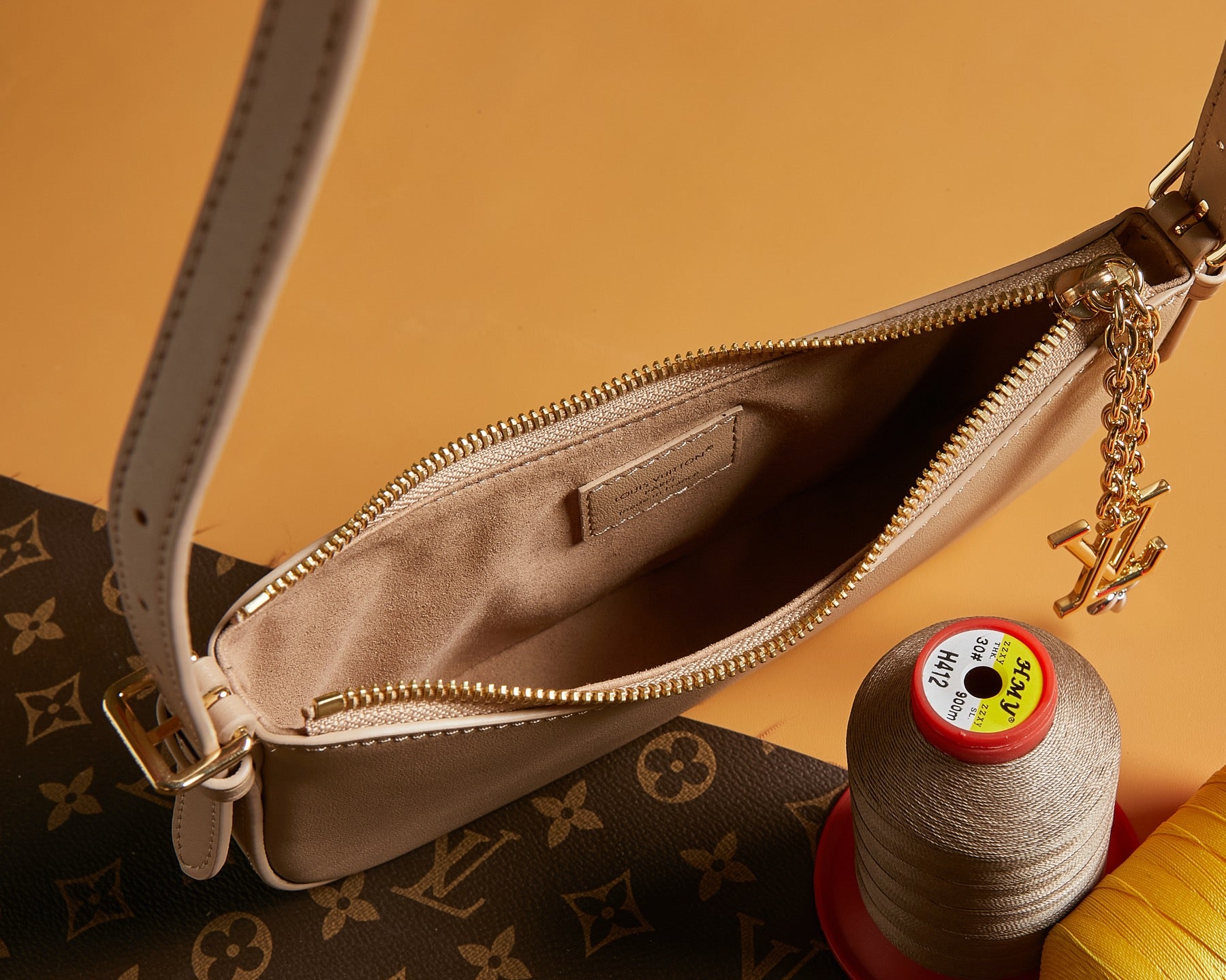 Louis Vuitton zip-top bag interior with beige lining, gold zipper and chain pull