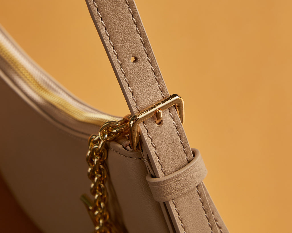 Louis Vuitton bag strap attachment with gold-tone clasp and stitched beige leather
