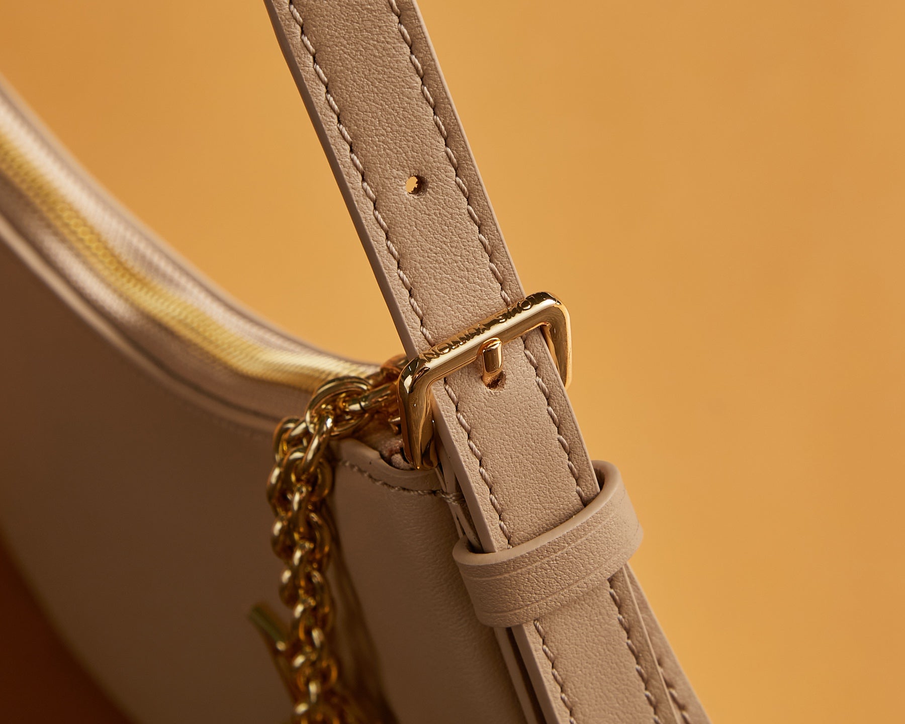 Louis Vuitton bag strap attachment with gold-tone clasp and stitched beige leather