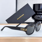 Balenciaga sunglasses in black with dark lenses, side view, gold temple logo
