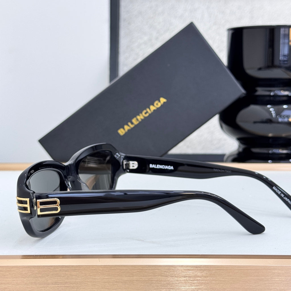 Balenciaga sunglasses in black with dark lenses, angled side view, gold temple logo