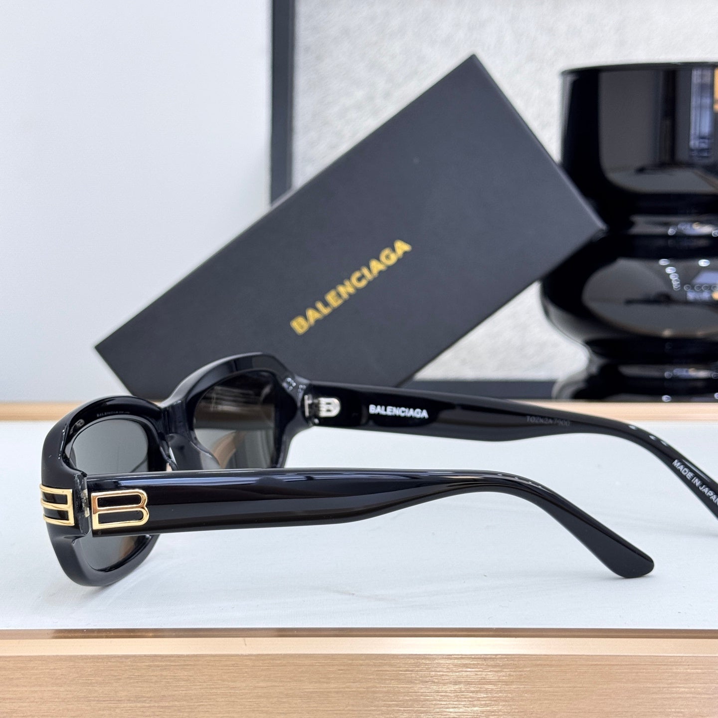 Balenciaga sunglasses in black with dark lenses, angled side view, gold temple logo