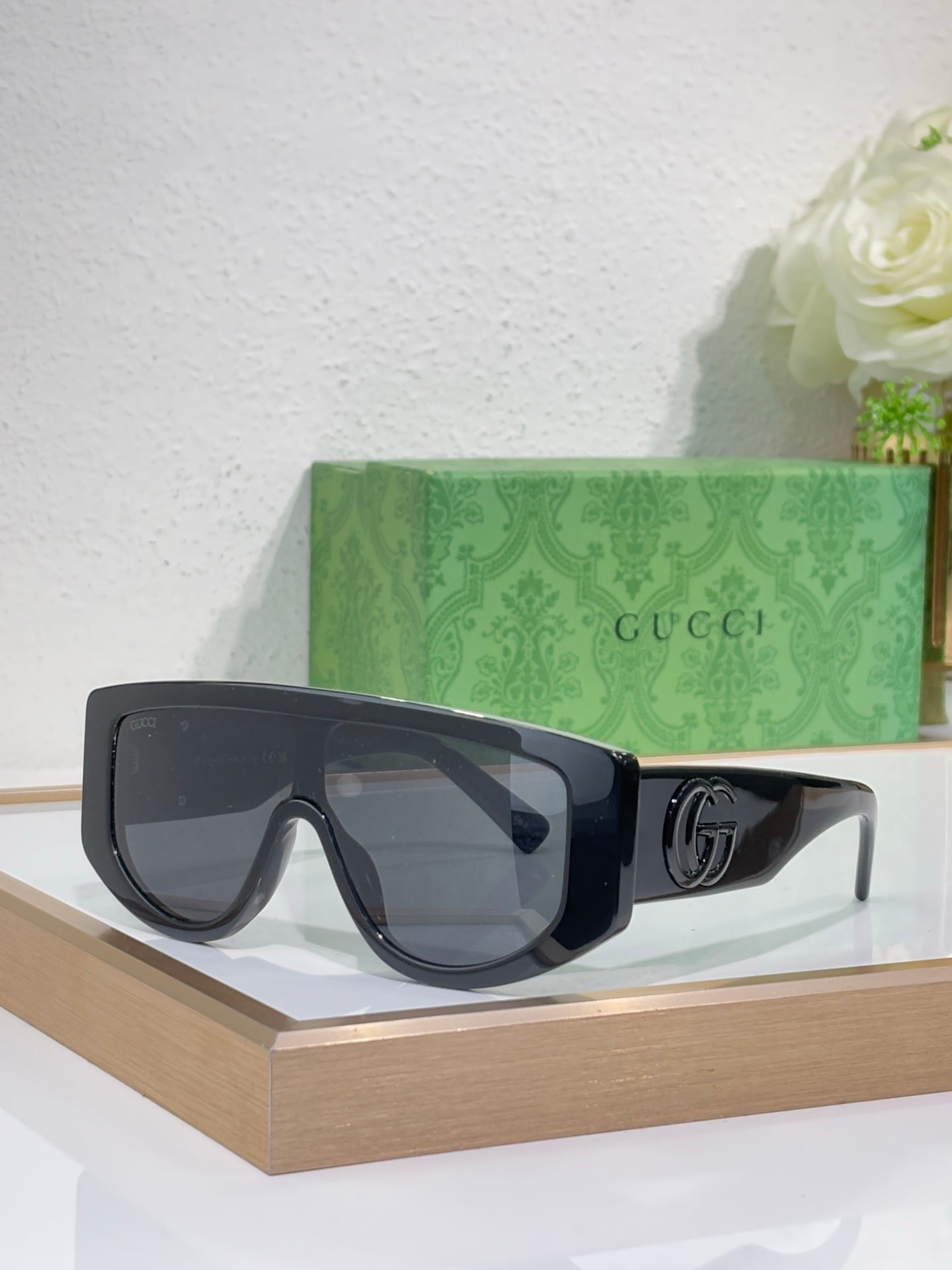 Gucci sunglasses with black oversized frames and dark tinted lenses, metal logo detail