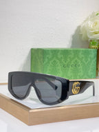 Gucci sunglasses with matte black oversized frames and dark tinted lenses, metal logo