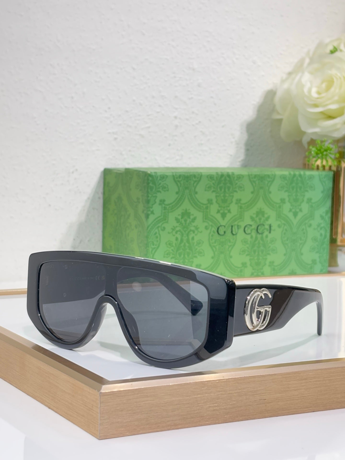 Gucci sunglasses with dark charcoal oversized frames and dark tinted lenses, metal logo