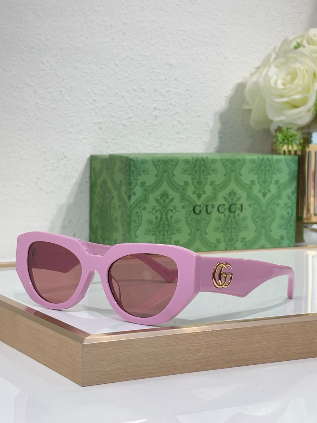 Sunglasses with purple frames, brown-tinted lenses, and a gold GG emblem on the temple.