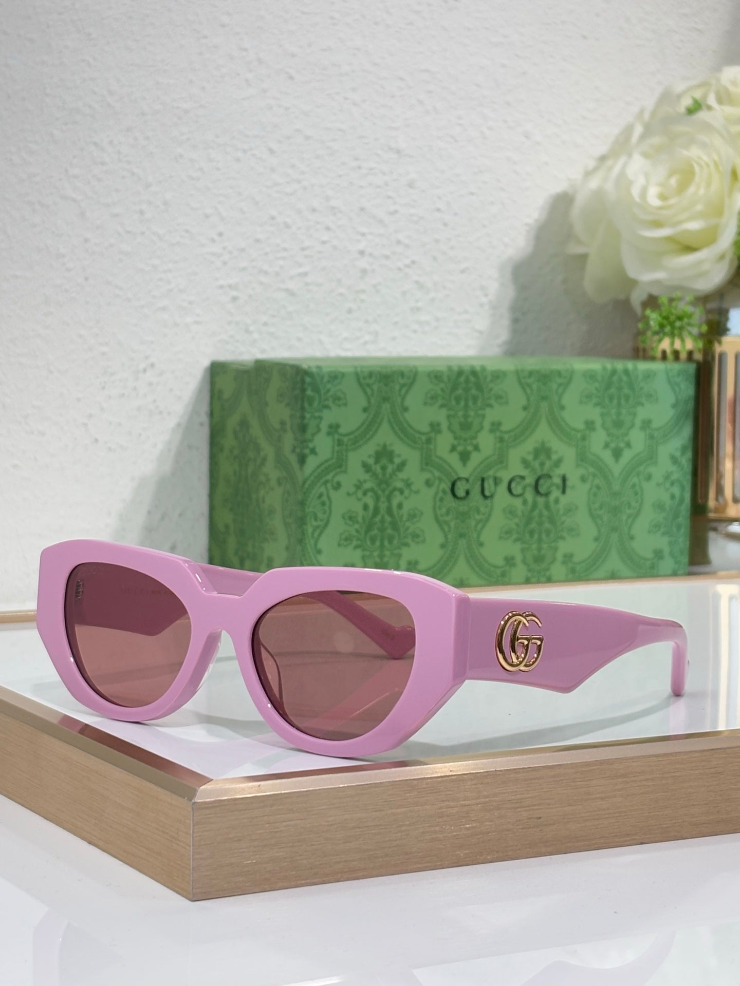 Sunglasses with purple frames, brown-tinted lenses, and a gold GG emblem on the temple.