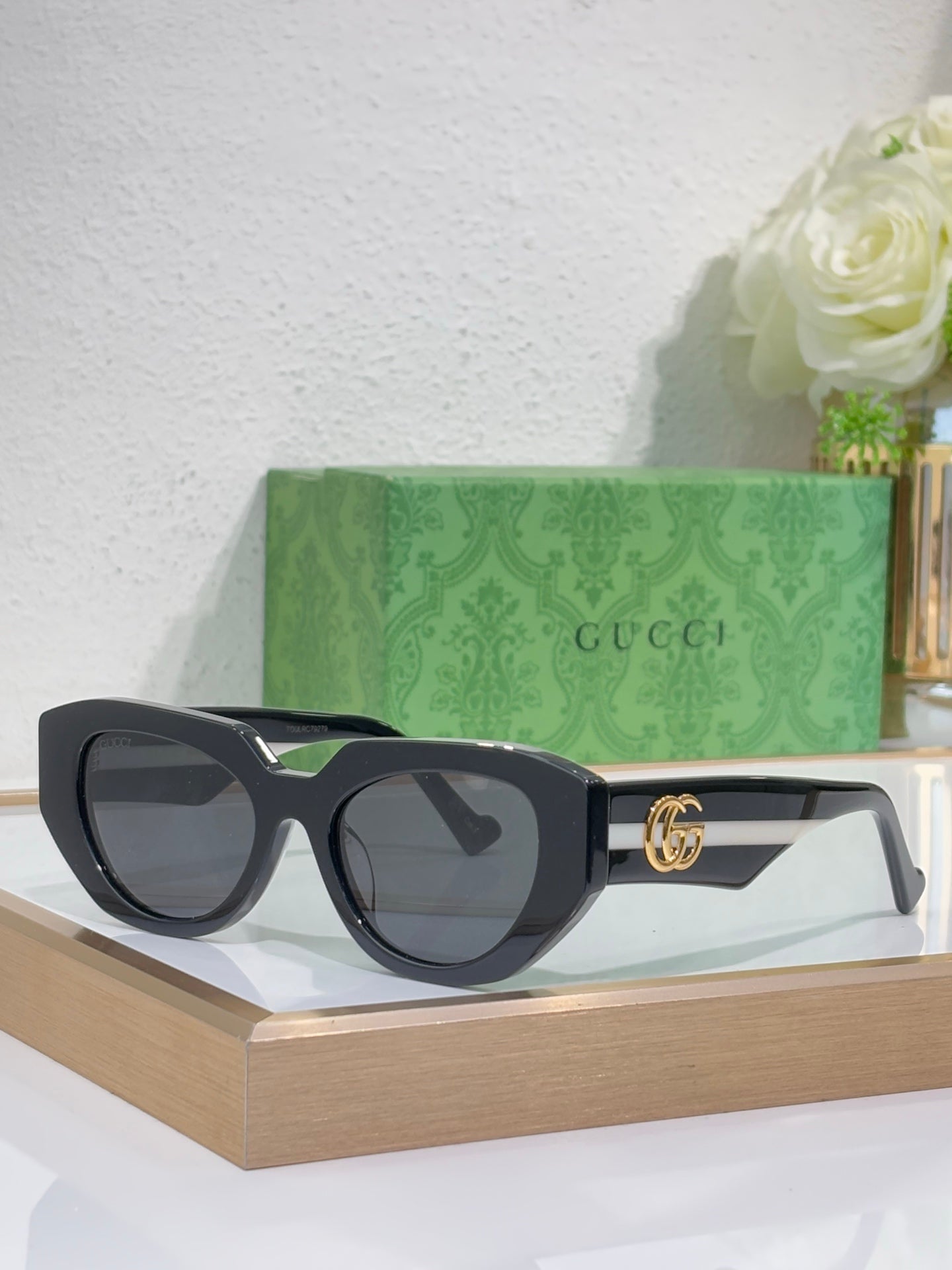 Sunglasses with black frames, dark lenses, and gold GG logo details on the temple.
