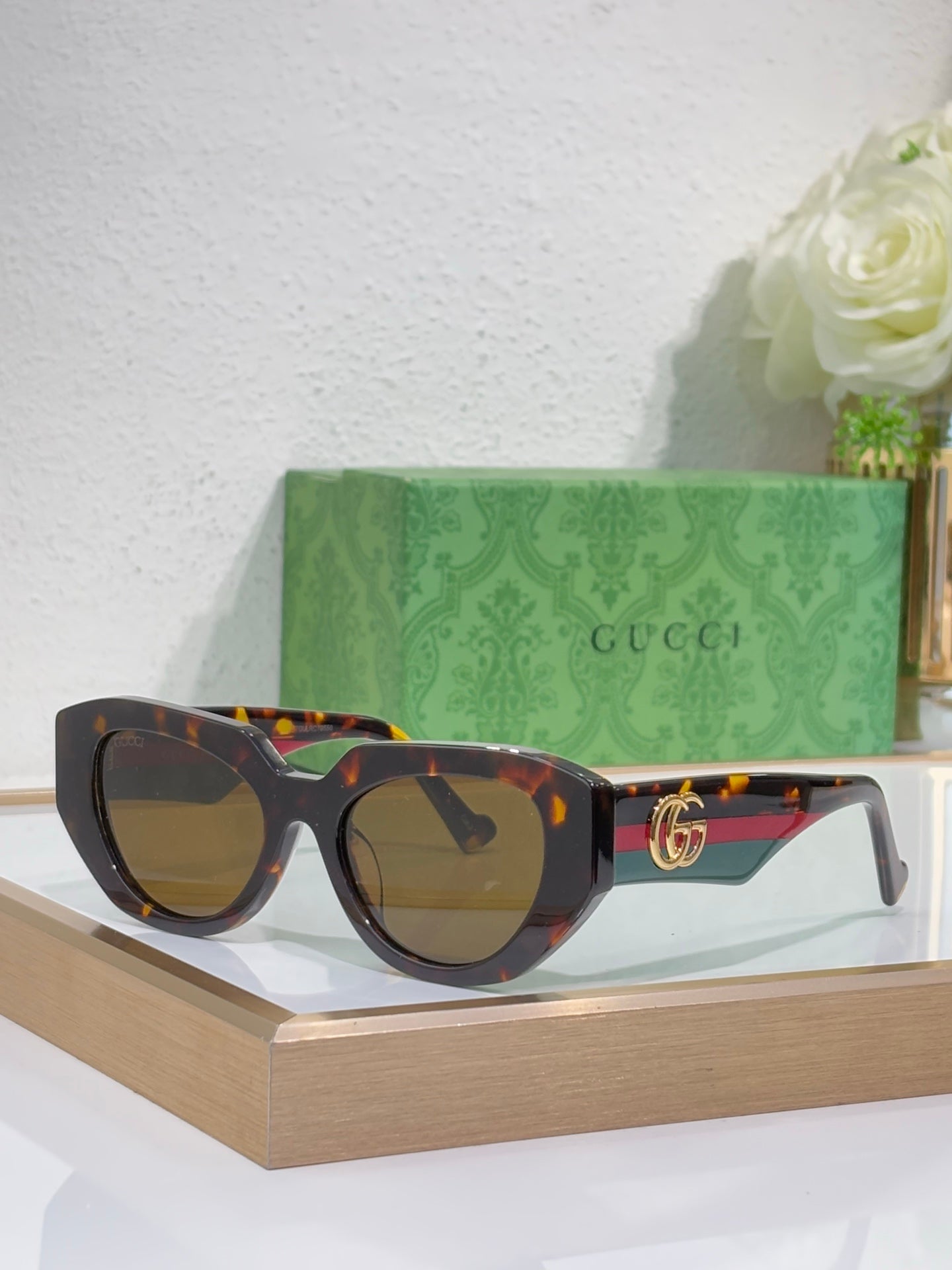 Sunglasses with black frames, tortoiseshell temple accents, and dark lenses with gold GG.