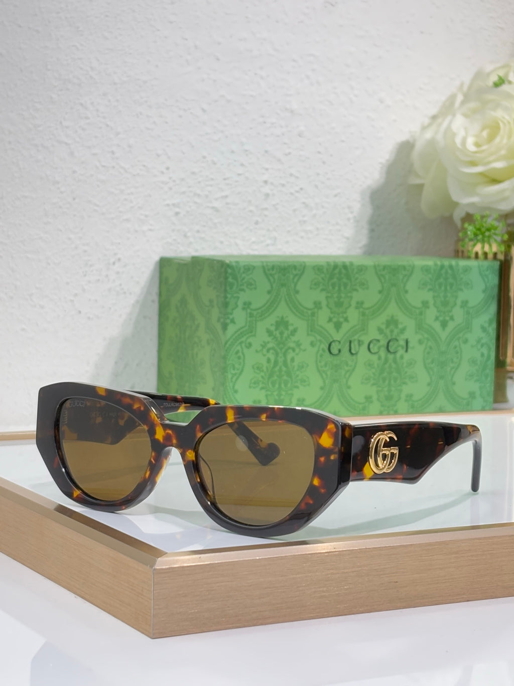 Sunglasses with tortoiseshell frames, amber lenses, and a gold GG emblem on the temple.