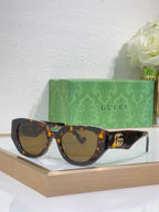 Sunglasses with tortoiseshell frames, amber lenses, and a gold GG emblem on the temple.