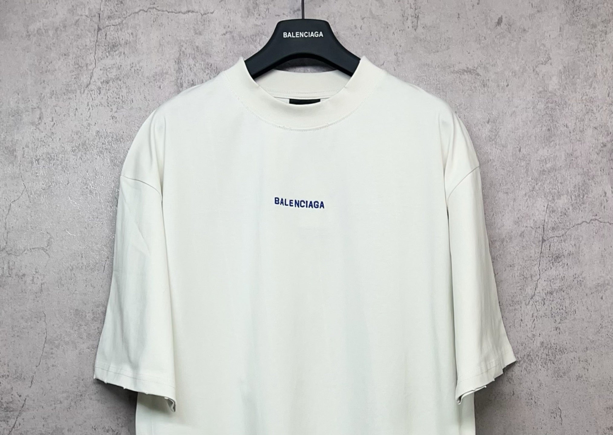 White short-sleeve T-shirt on hanger with small black Balenciaga chest logo
