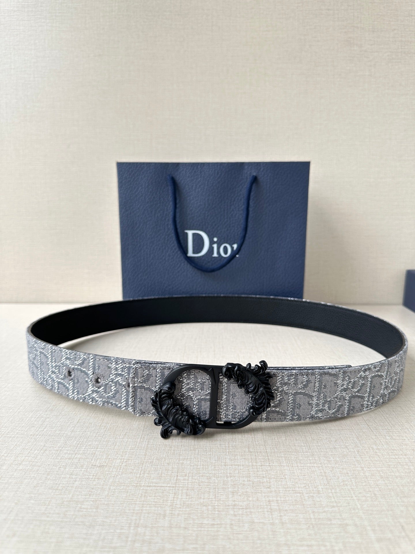 Belt with silver-gray textured strap and black ornate buckle