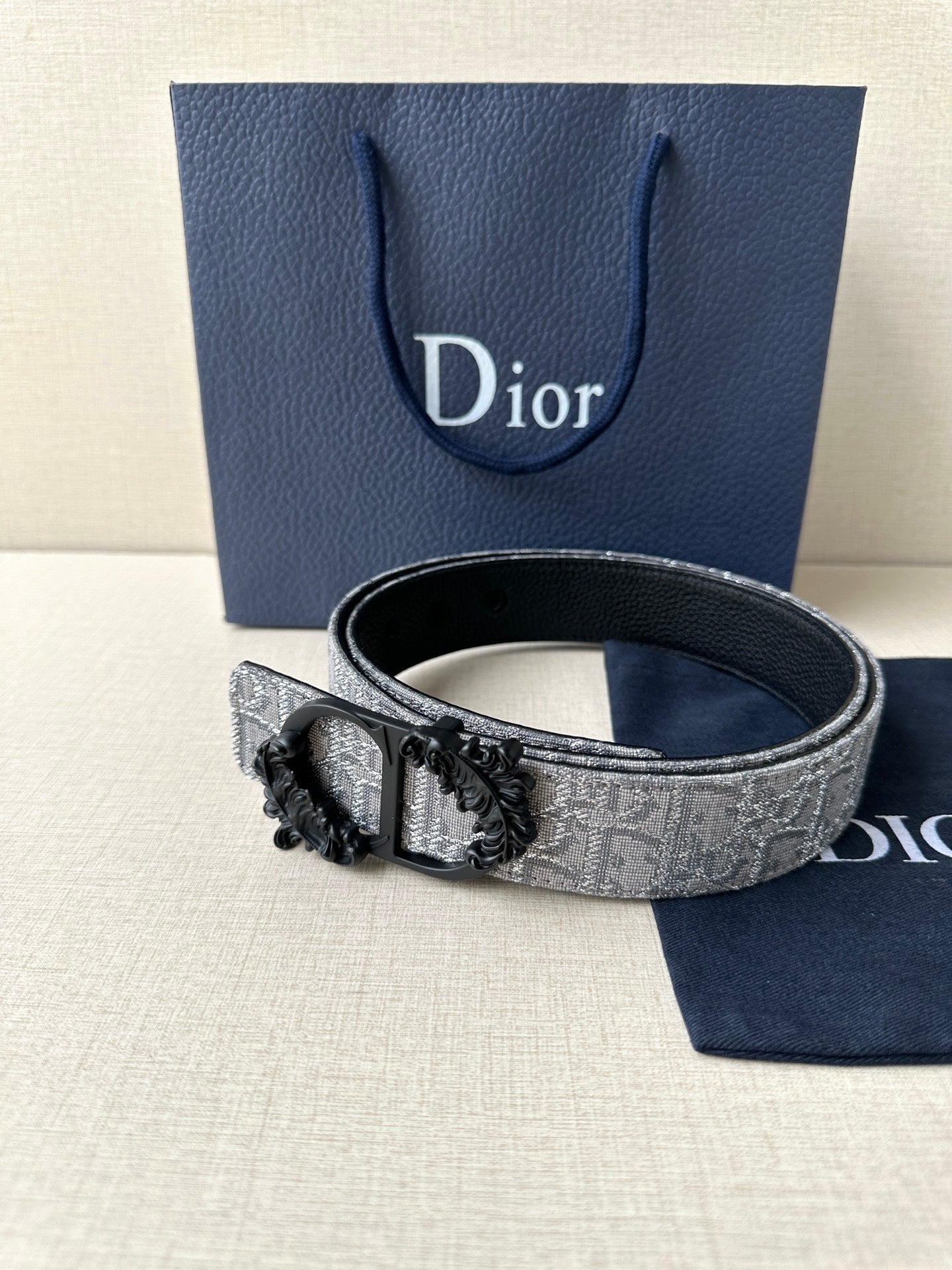 Belt with silver-gray patterned strap and black buckle, angled view