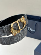 Dior belt close-up: silver-gray monogram strap with gold-toned buckle and bar clasp.