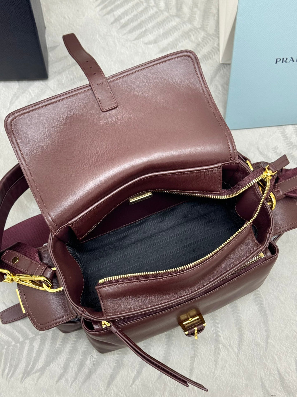 Burgundy Prada mini shoulder bag with open top and gold zipper pulls