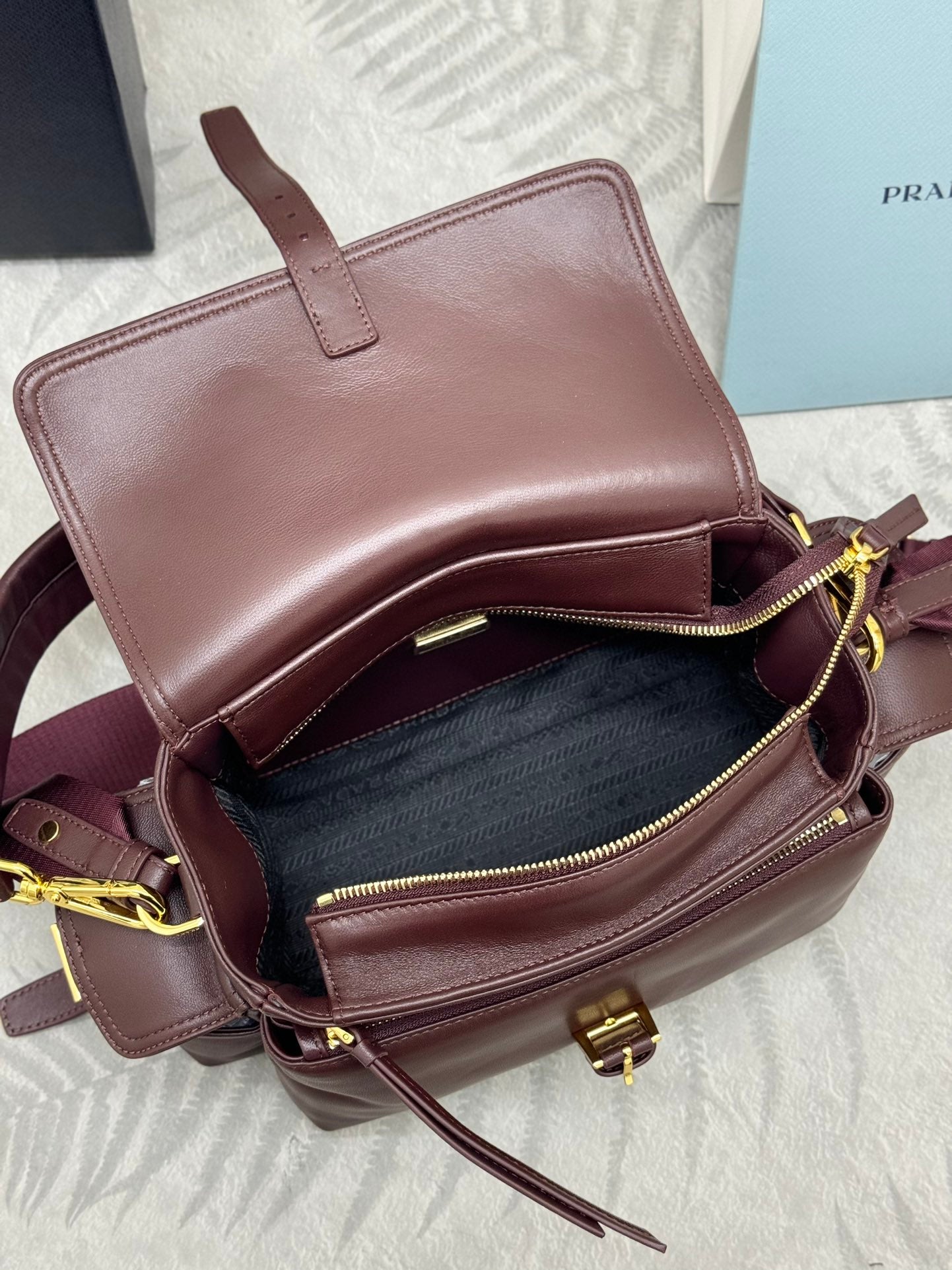 Burgundy Prada mini shoulder bag with open top and gold zipper pulls