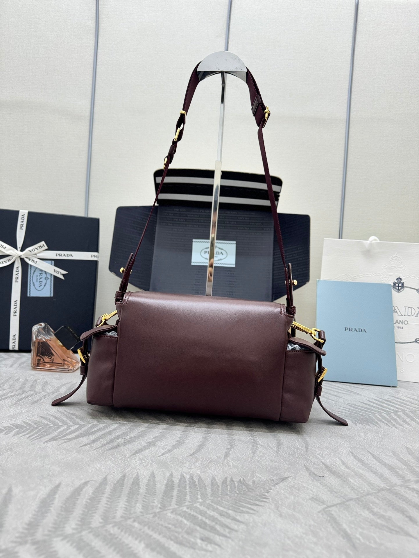Burgundy Prada satchel bag with front flap, dual straps, and gold hardware