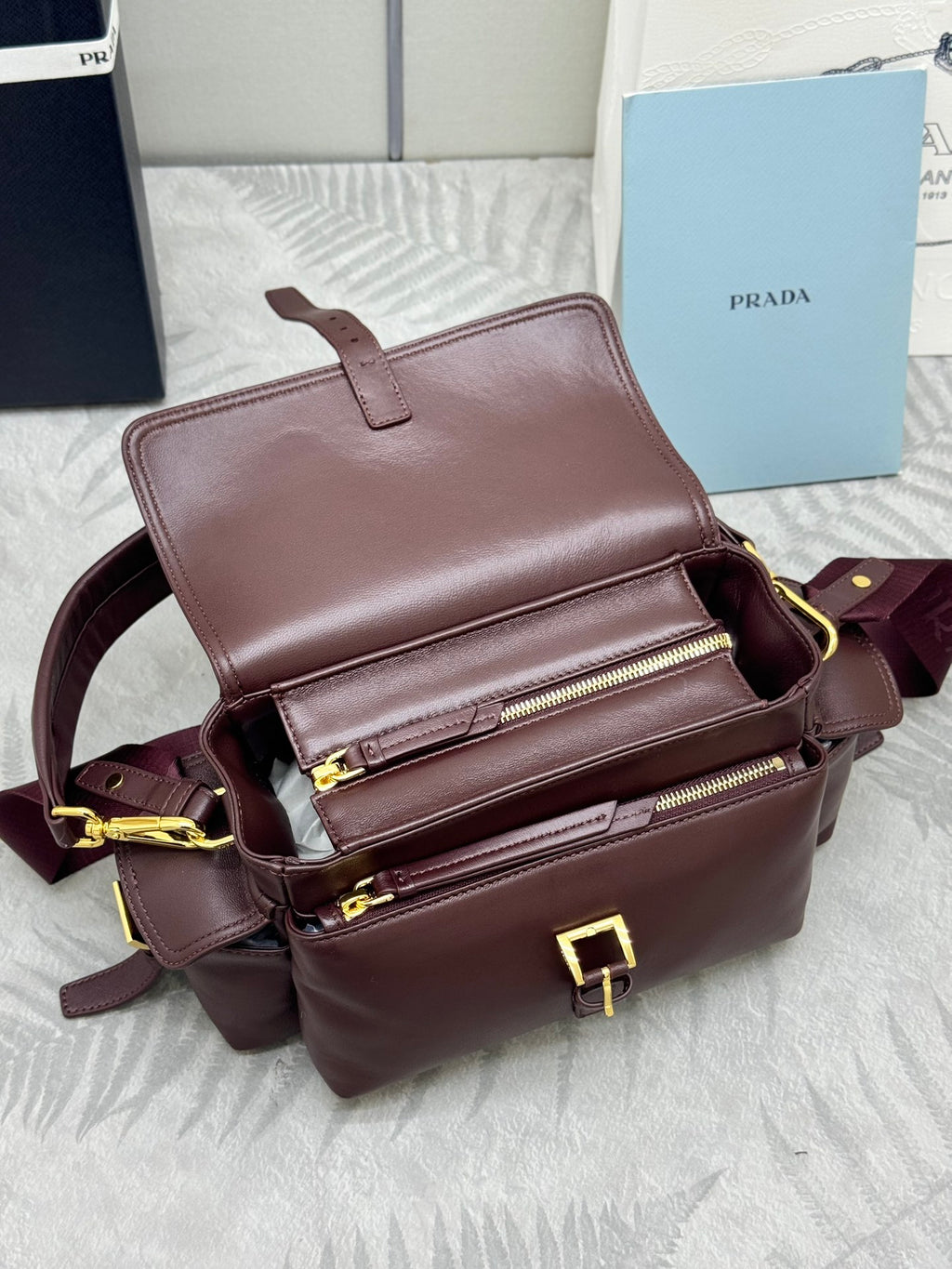 Burgundy Prada shoulder bag with flap front, two zippers, and gold accents
