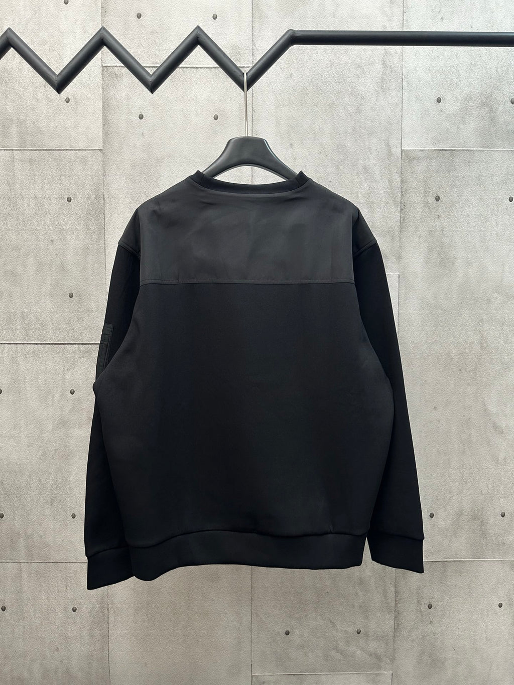 Black crew-neck sweatshirt with long sleeves on hanger