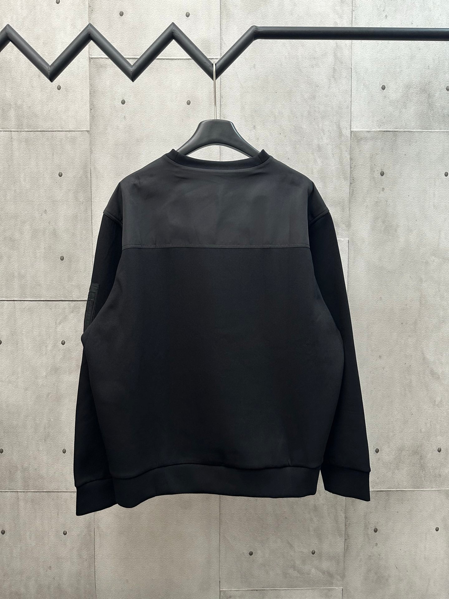 Black crew-neck sweatshirt with long sleeves on hanger