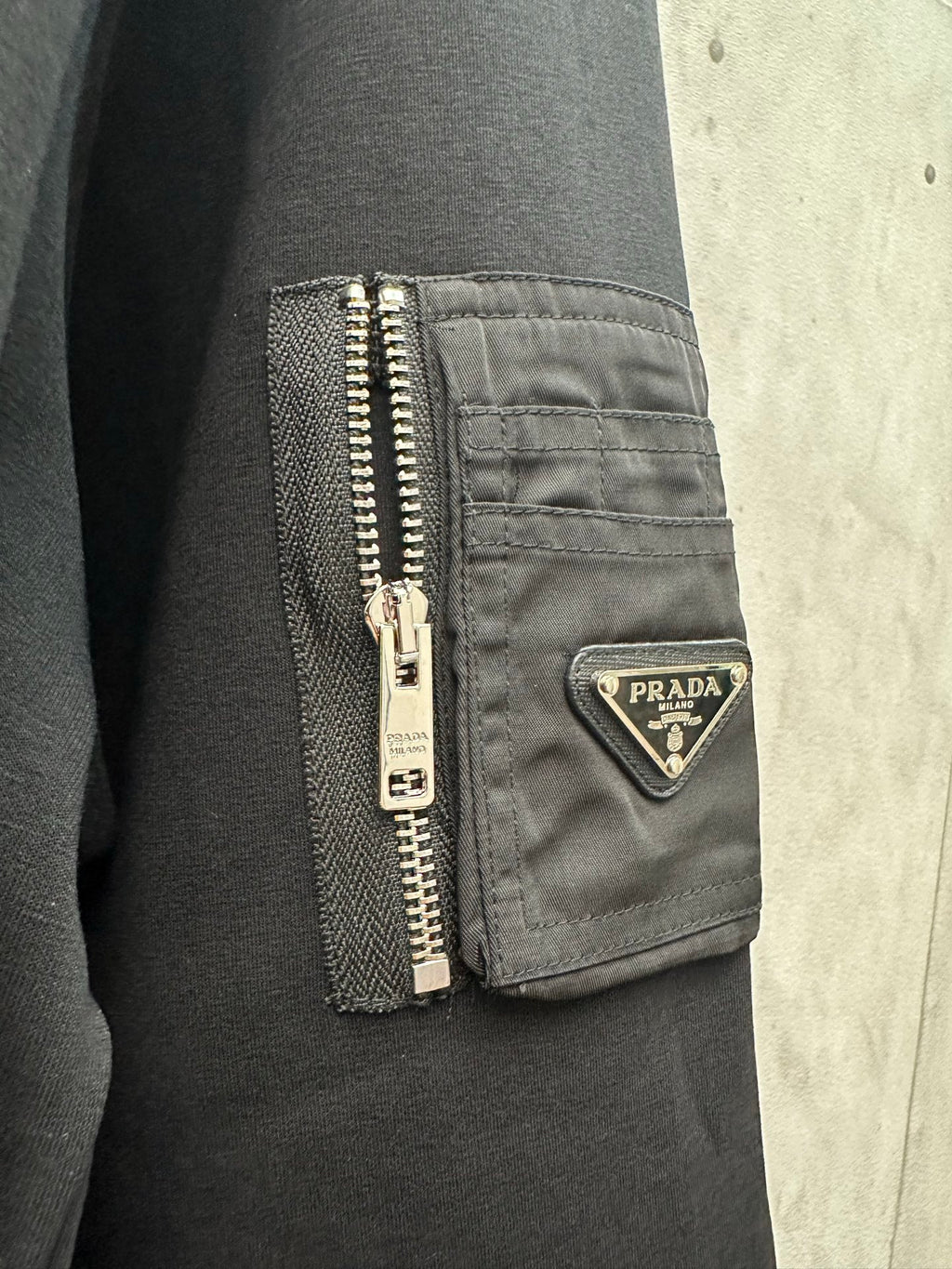 Black sweatshirt pocket with zipper and Prada logo badge