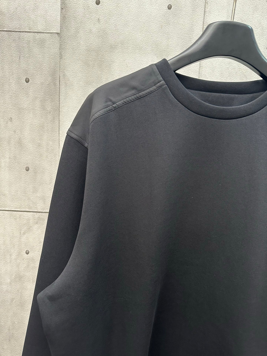 Black crew-neck sweatshirt with long sleeves and shoulder seam