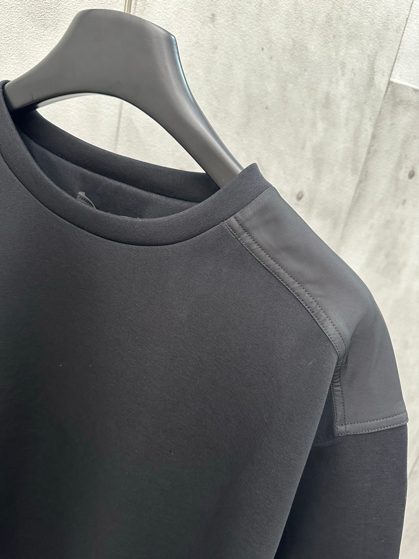 Black crew-neck sweatshirt with shoulder seam and sleeve panel