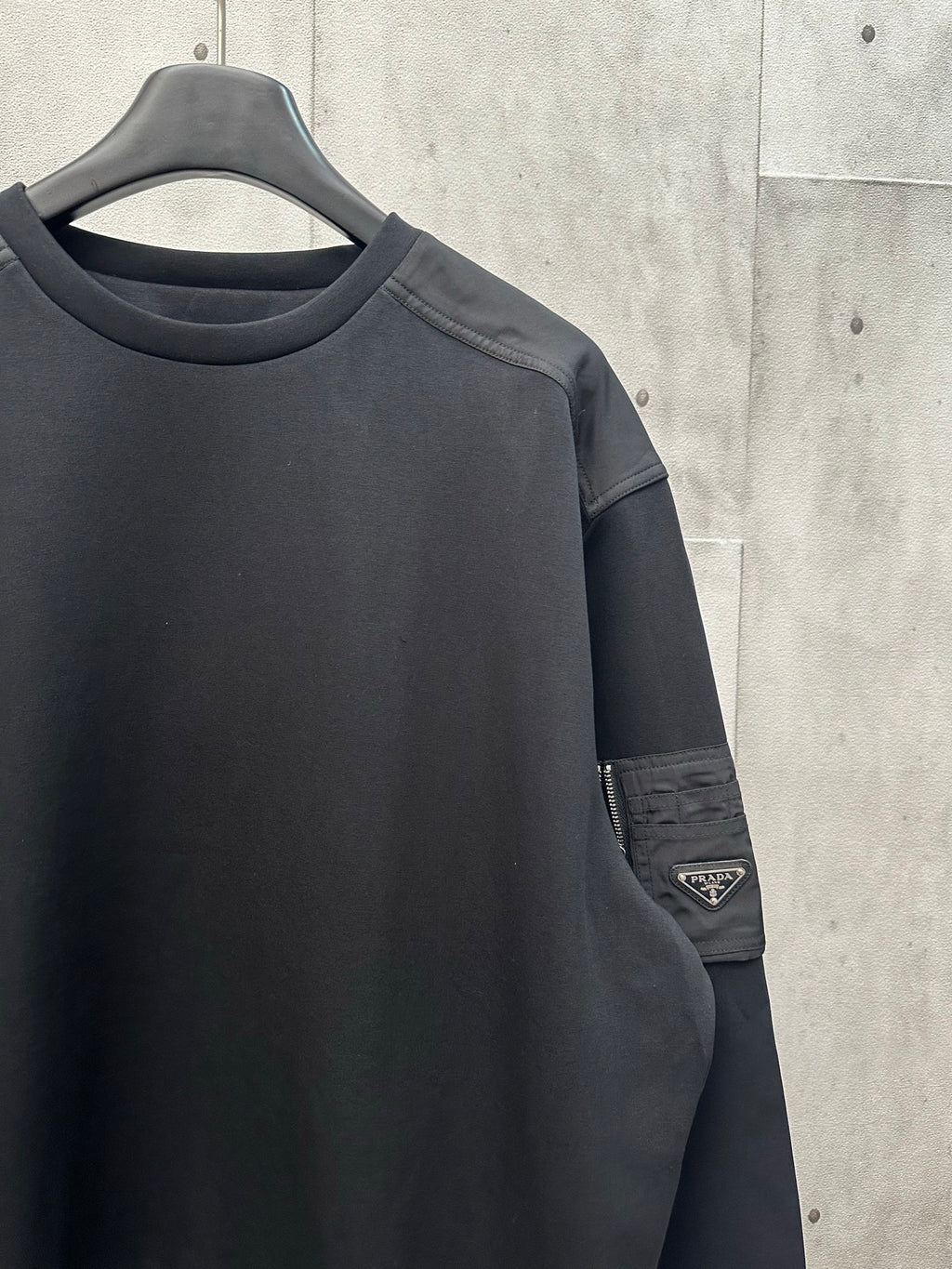 Black sweatshirt sleeve with Prada logo patch on arm