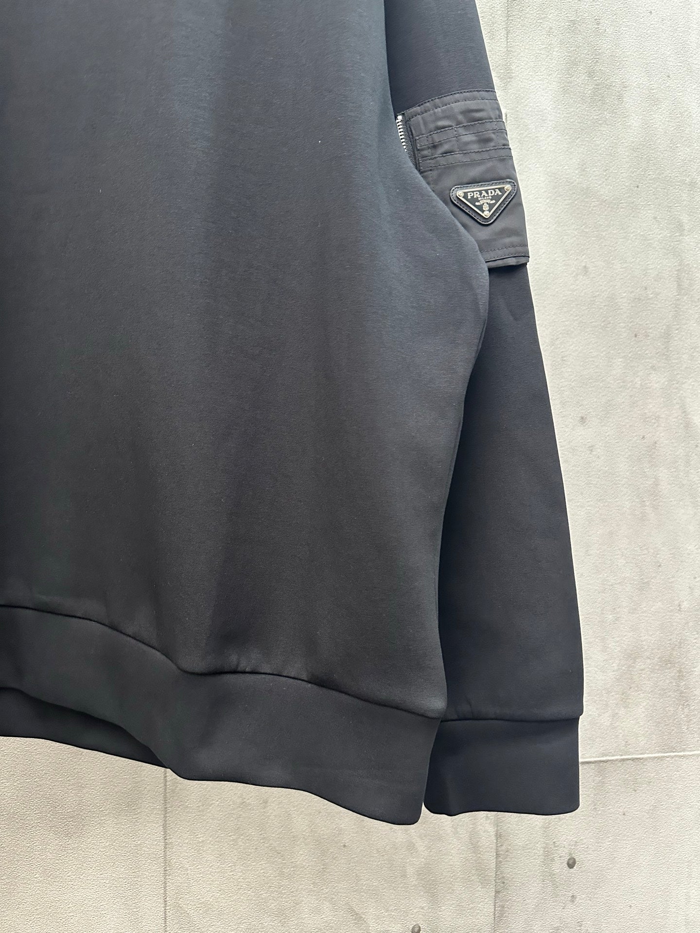 Black sweatshirt hem with visible stitching and sleeve patch