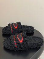Black teddy-fleece slide sandals with red heart logo on front strap, BALENCIAGA text