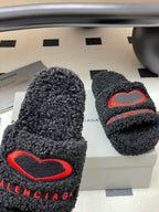 Black teddy-fleece slide sandals with large red heart logo and BALENCIAGA lettering