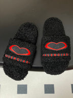 Pair of black teddy-fleece slide sandals with red heart emblem and red BALENCIAGA strap text