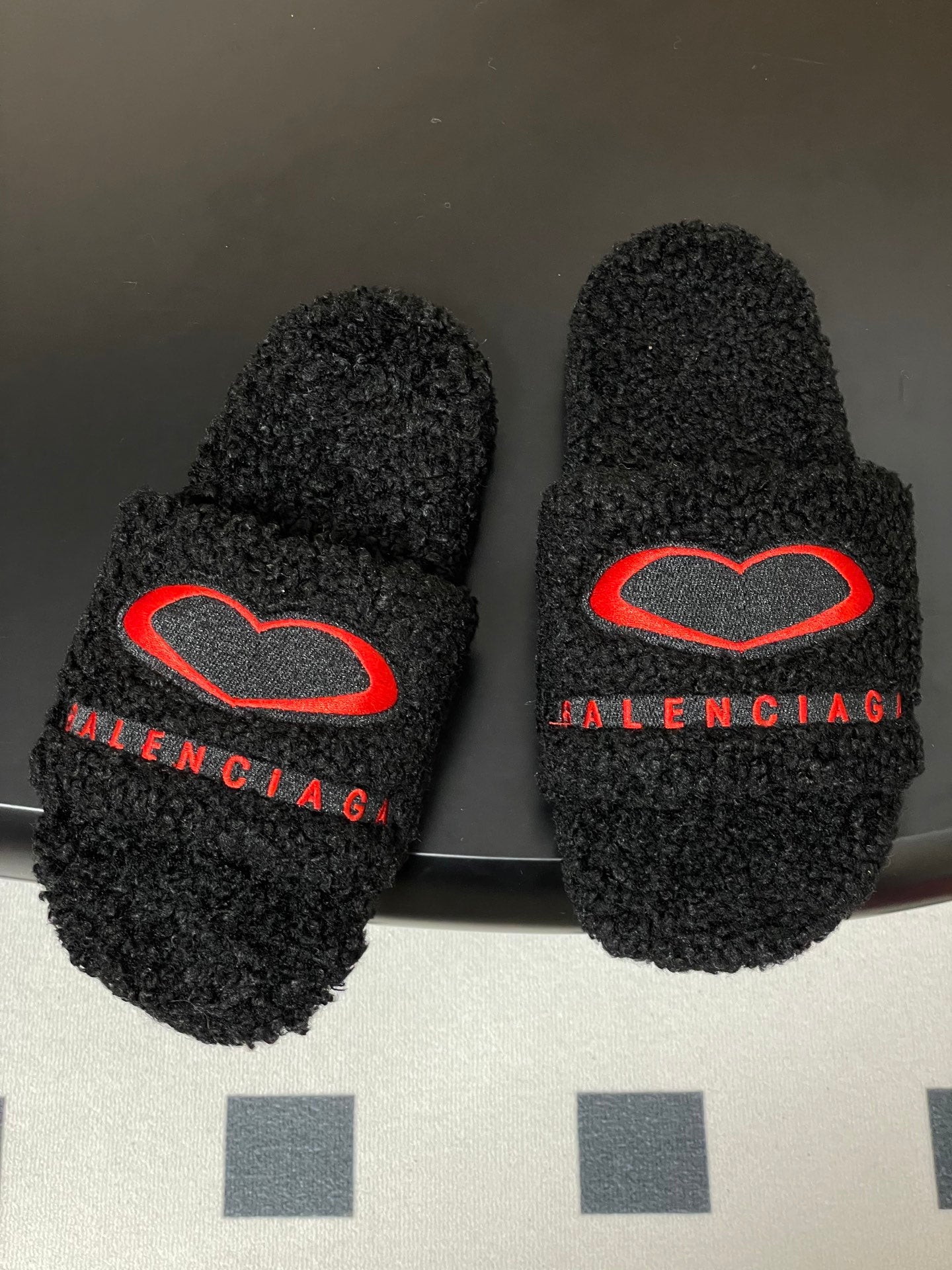 Pair of black teddy-fleece slide sandals with red heart emblem and red BALENCIAGA strap text