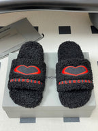 Black teddy-fleece slide sandals with red heart emblem on strap and BALENCIAGA lettering
