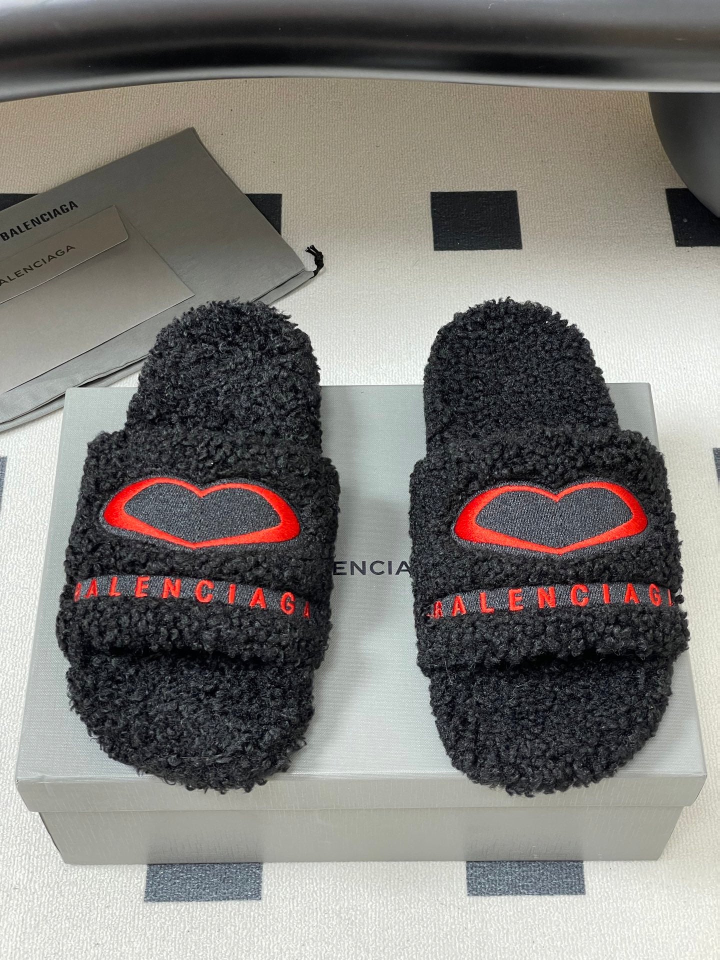 Black teddy-fleece slide sandals with red heart emblem on strap and BALENCIAGA lettering