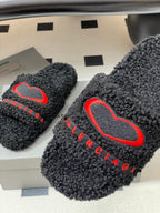 Black teddy-fleece slide sandals with red heart outline logo and red BALENCIAGA text