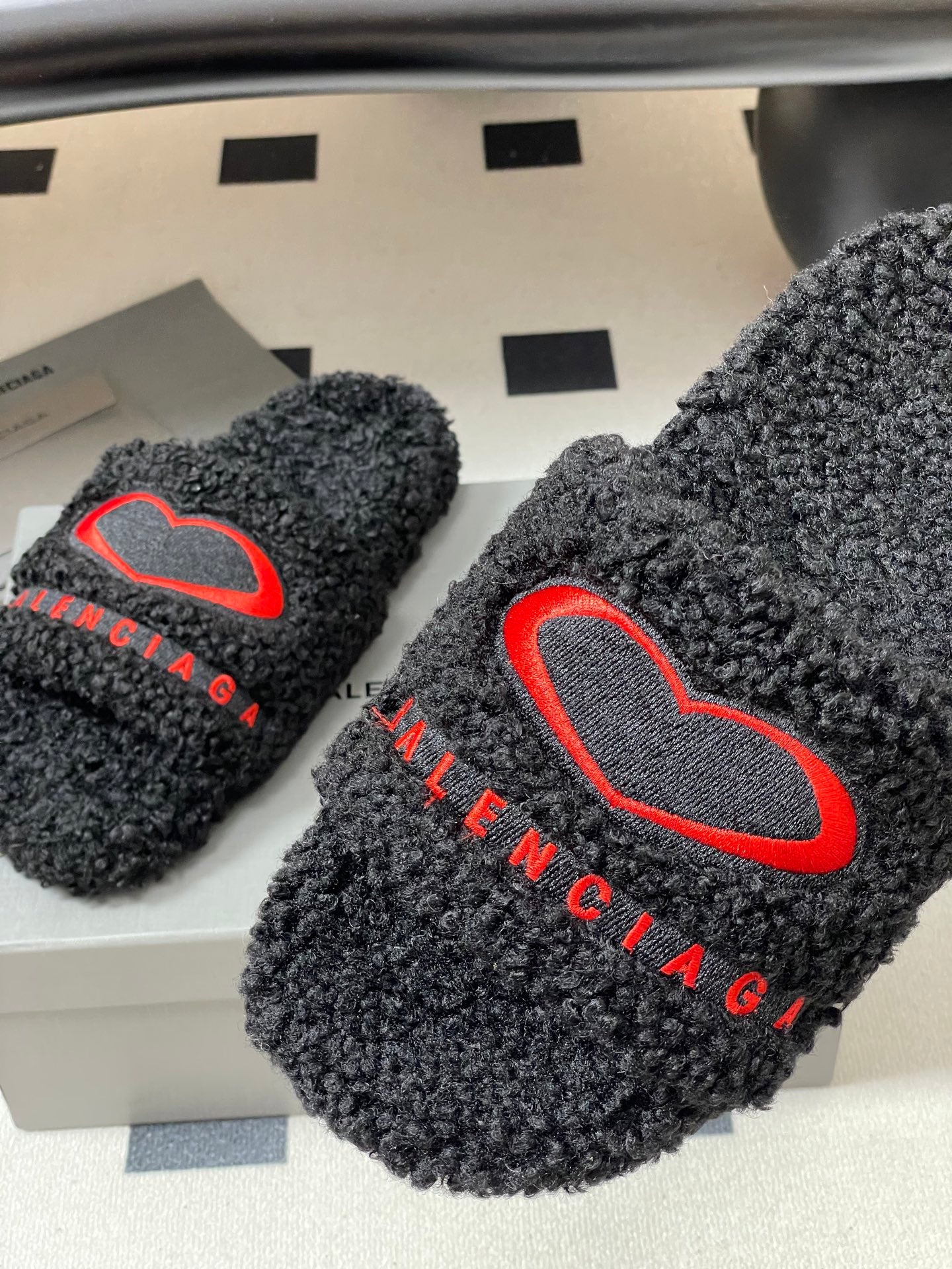 Black teddy-fleece slide sandals with red heart outline logo and red BALENCIAGA text