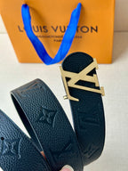 Louis Vuitton belt end and buckle close-up on dark leather with embossed LV pattern