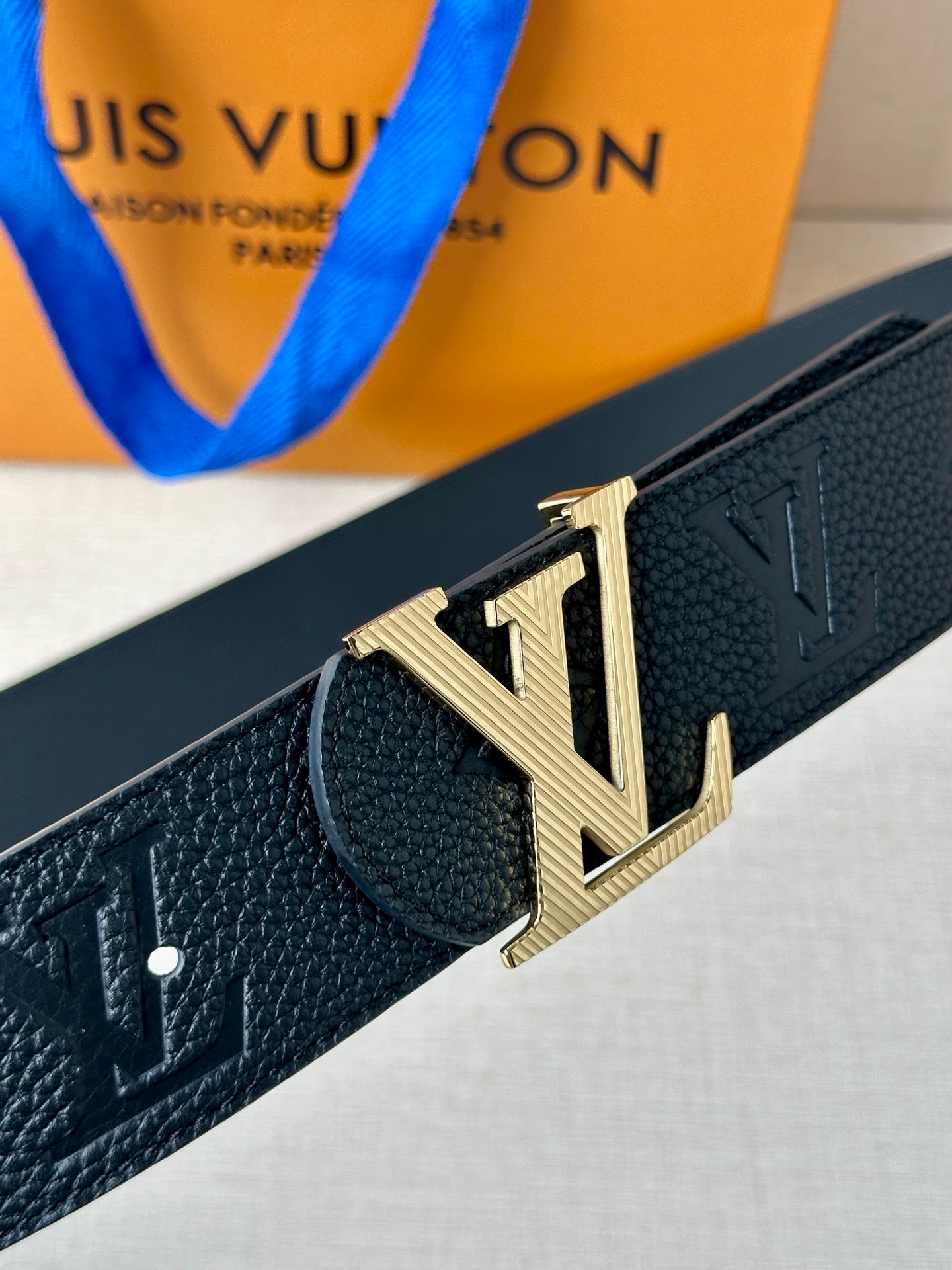 Louis Vuitton belt close-up: dark textured leather and gold-tone LV buckle detail