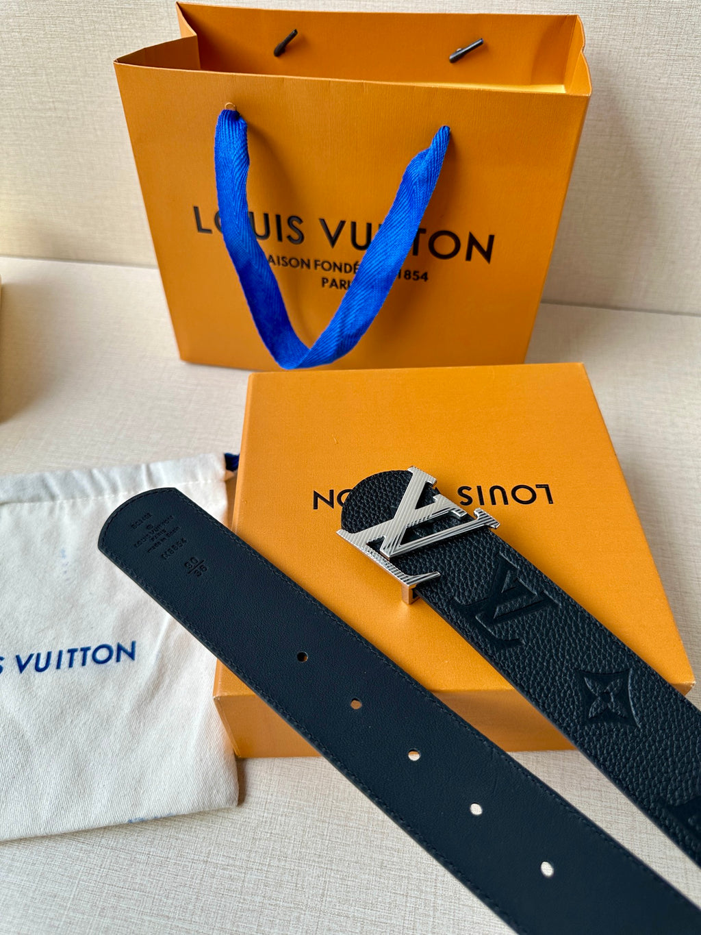 Louis Vuitton belt and strap end with holes; dark textured leather with LV branding