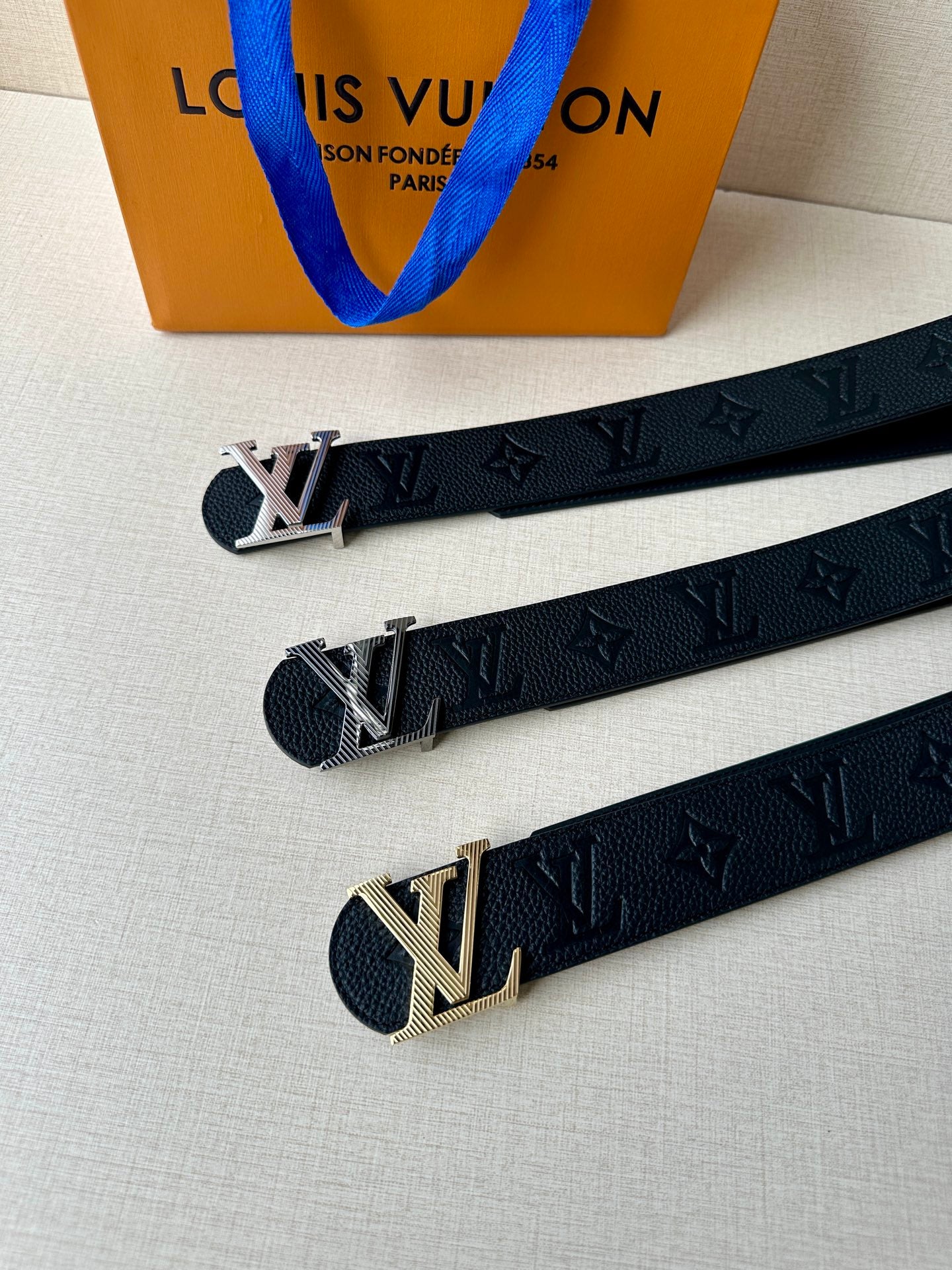 Louis Vuitton belt set laid out: dark leather straps with gold-tone LV buckles