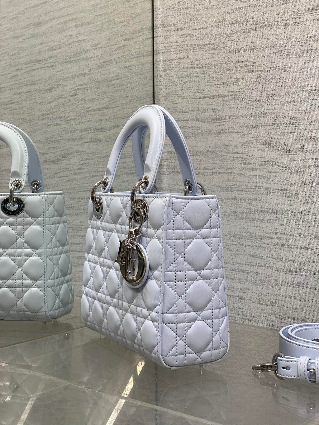 Dior quilted light blue handbag with top handles and gold hardware, shown in side view