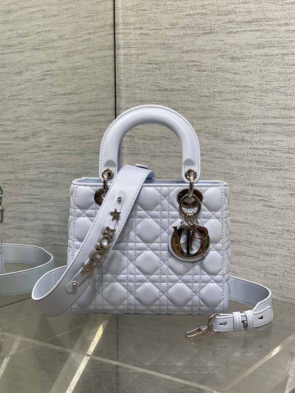 Quilted light blue Dior handbag with top handles, gold hardware, and removable strap