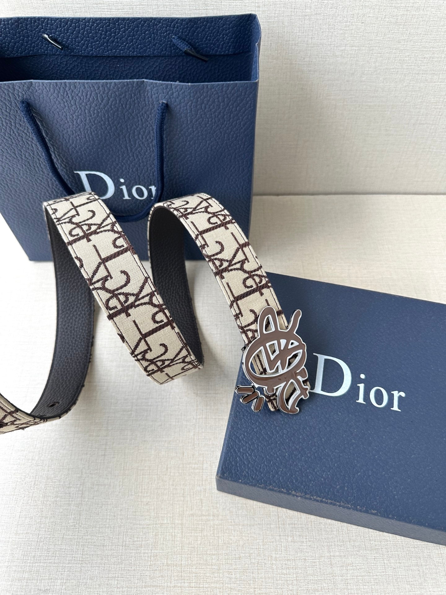 Dior belt shown with looped strap and gold-toned Dior emblem buckle