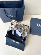 Dior belt with beige logo strap and silver-gold emblem buckle, folded
