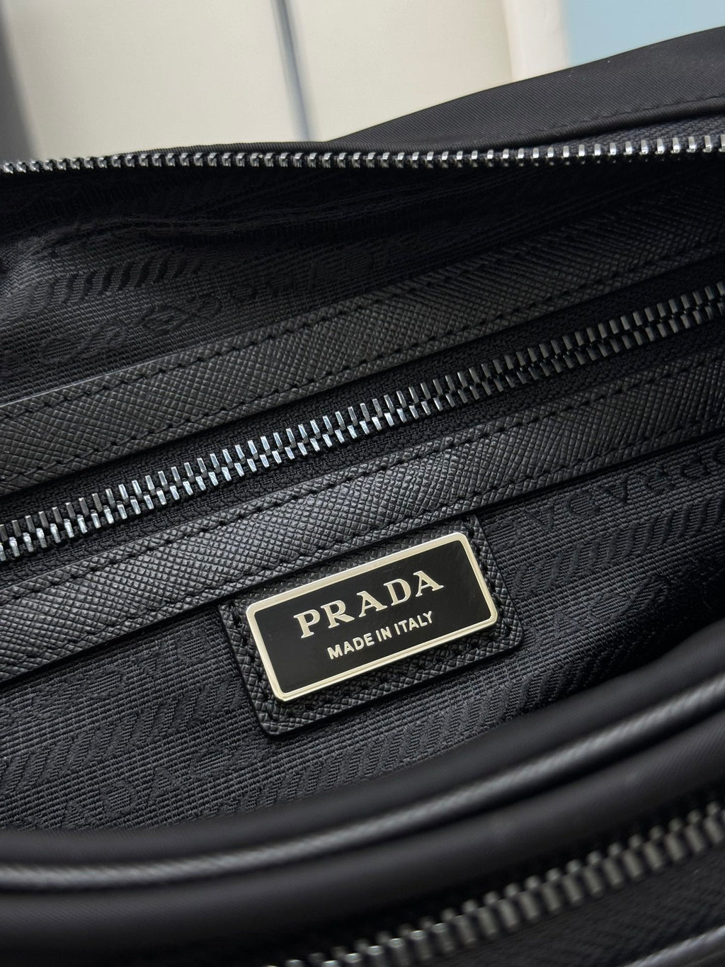 Prada bag interior side view with dual zippers and Prada logo label
