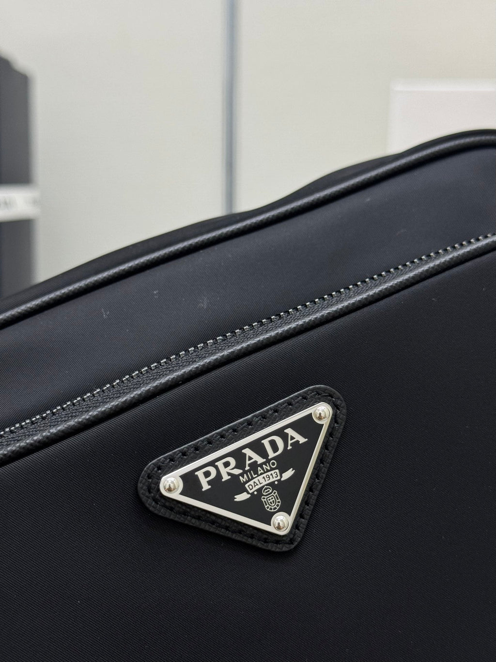 Prada bag close-up of front logo patch on black leather with stitched edge