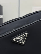 Prada bag close-up of front logo patch on black leather with stitched edge