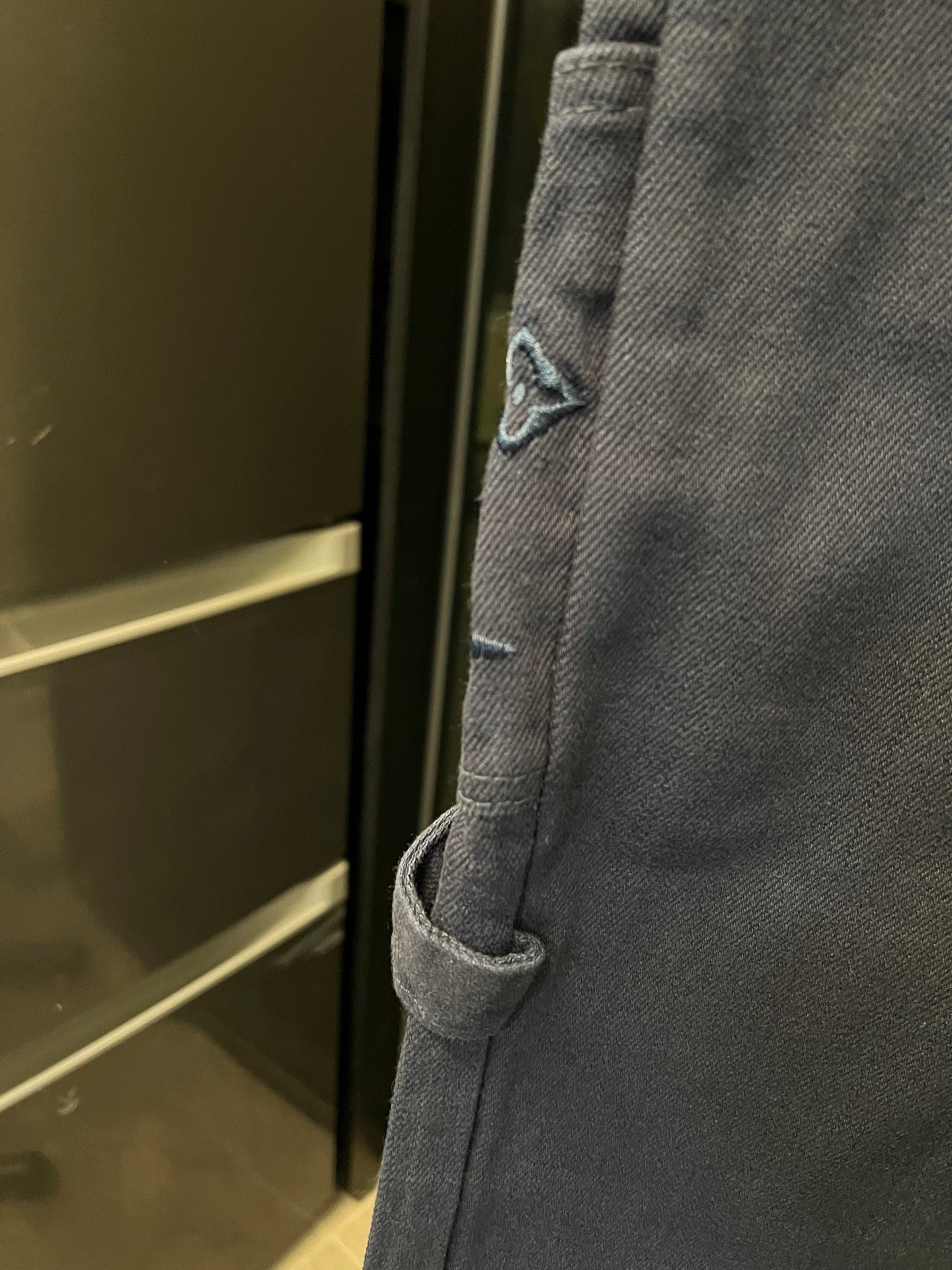 Dark blue denim cargo pants with angled side pocket and stitched seam detail